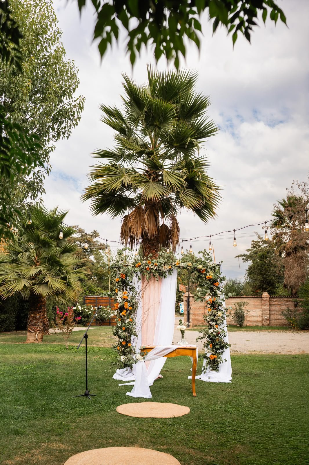 Arco de ceremonia con flores naranjas y palmeras