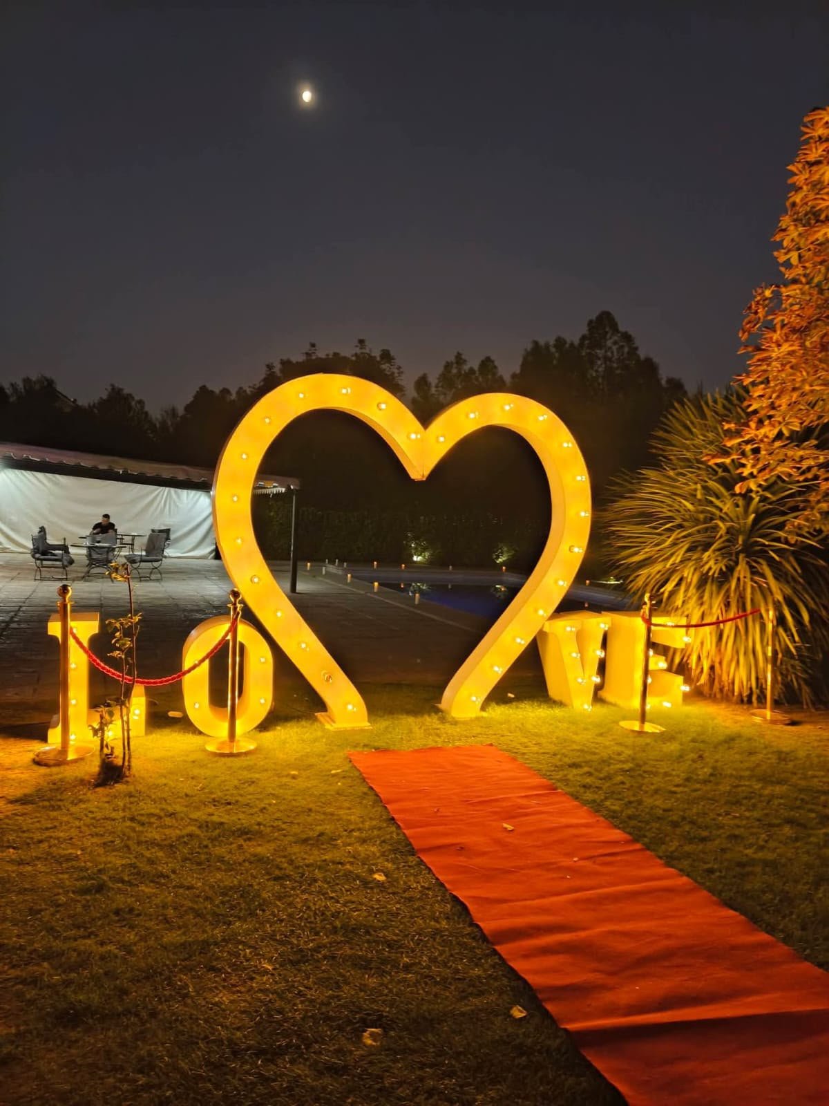 Letras LOVE iluminadas junto a la piscina con alfombra roja