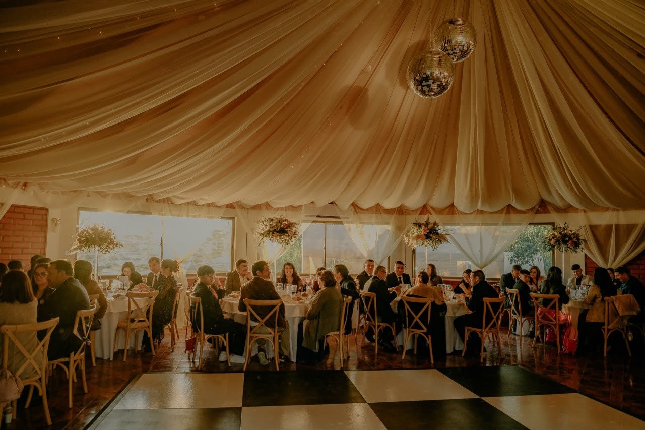 Salón cerrado montado con mesas, techo entelado y pista de baile